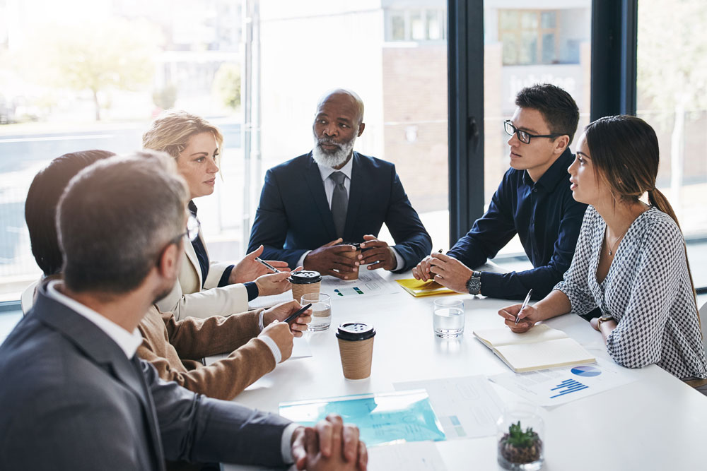 6 profesionales de los negocios reunidos en una sala de juntas en un día soleado