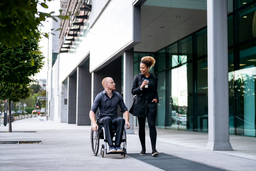 Man in a wheelchair walking and talking with woman