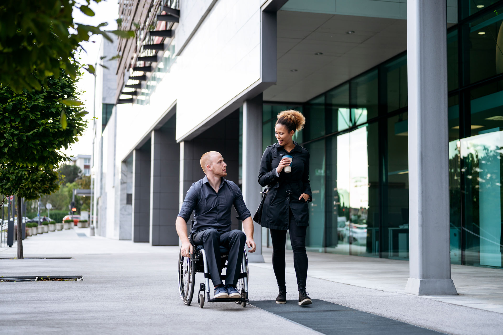 Man in a wheelchair walking and talking with woman