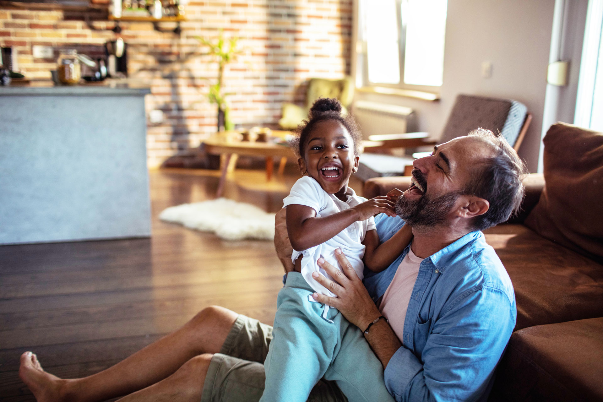 A man and a young girl playing on the floor of a modern living room