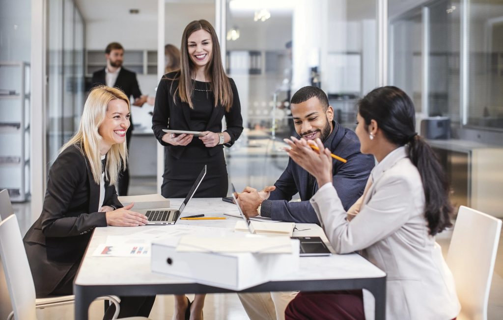 4 smiling coworkers meeting together in conference room