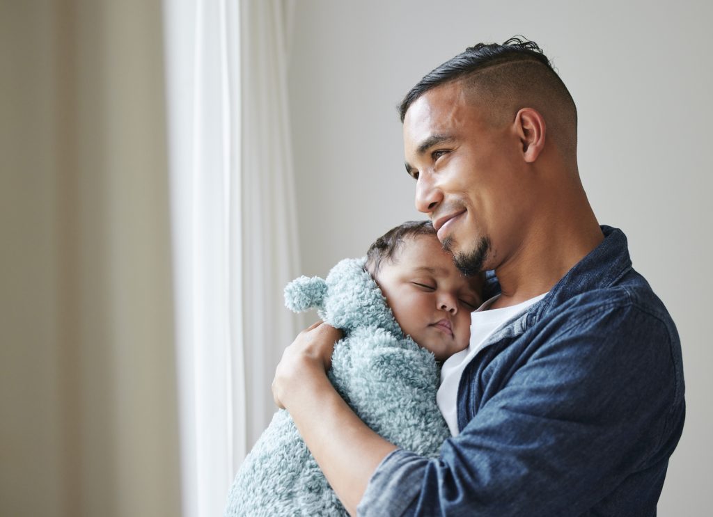 Shot of a young father embracing his baby at home