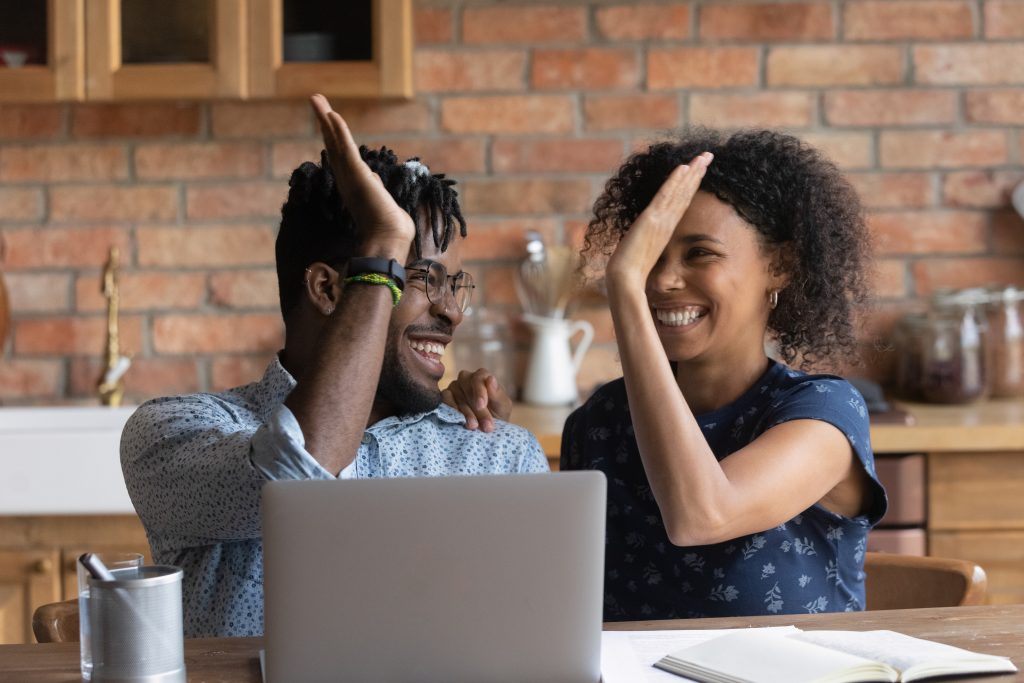 Couple high-fiving in front of laptop