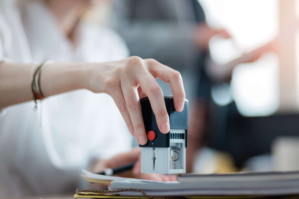 Woman's hand holding a stamp while stamping document